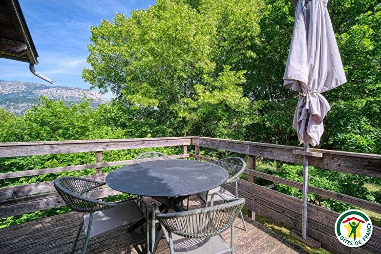 La terrasse fermée surplombant le jardin avec vue sur le massif du Glandasse (Vercors) et le plateau de Solaure 