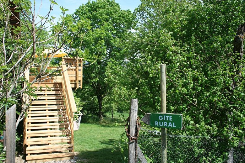 L'entrée du gîte (escalier avec rampe) et la terrasse surplomblant le jardin clôturé et ombragé